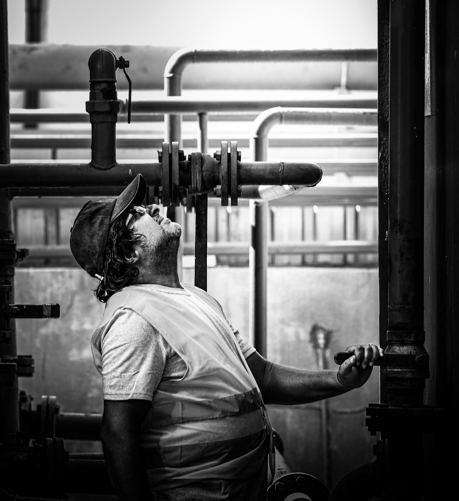 Technician inspecting overhead pipework and valves