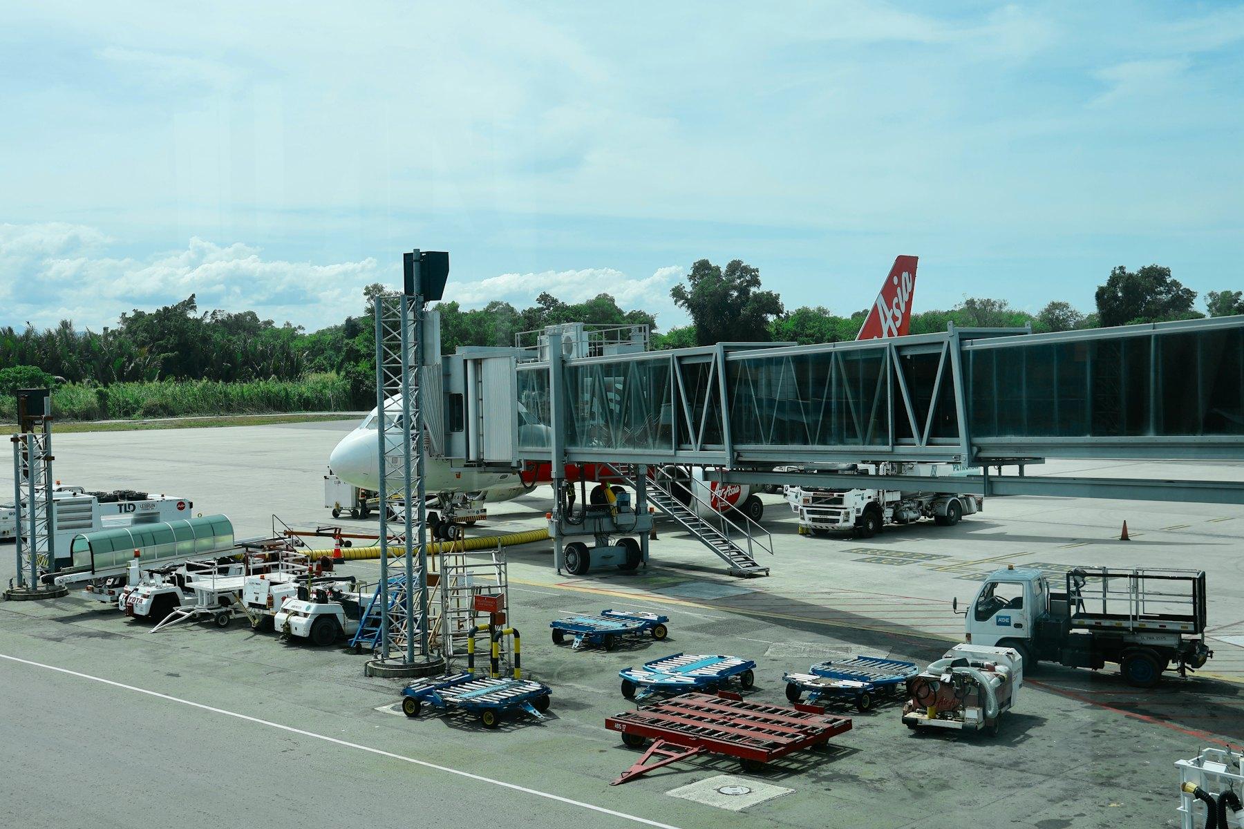 Aircraft at a jet bridge with ground support equipment on the apron