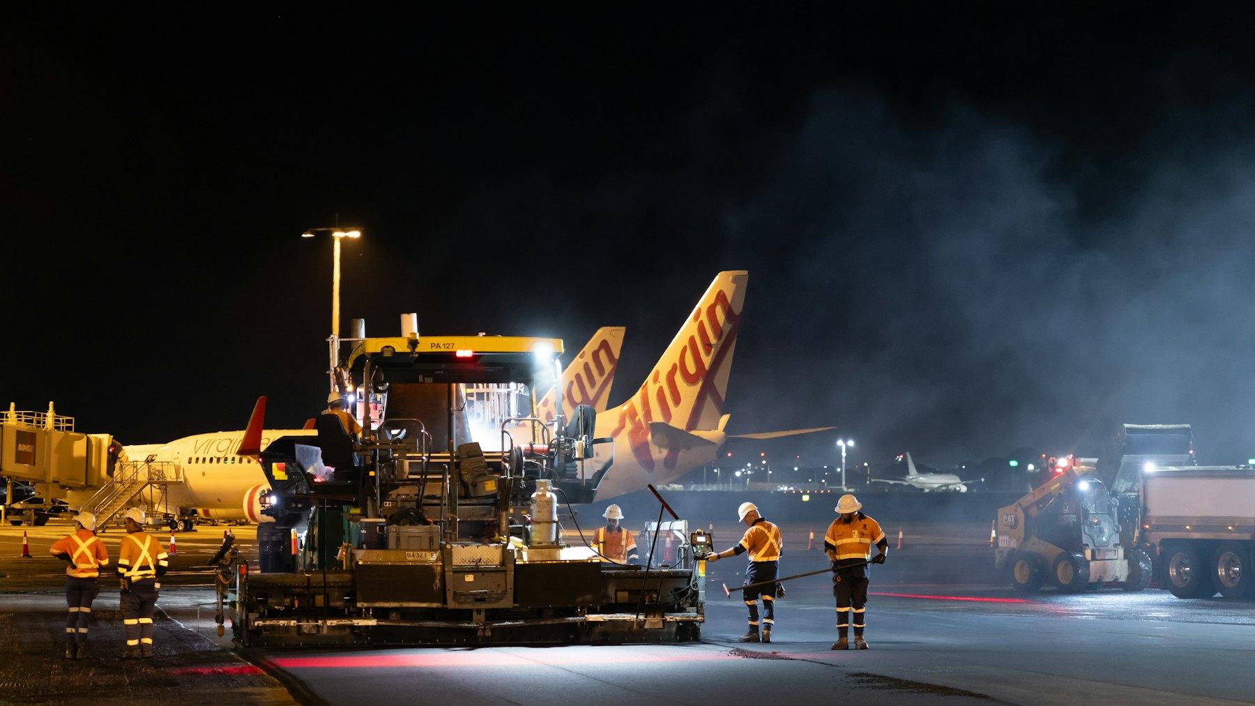Airport crew working on the apron at night beside parked aircraft